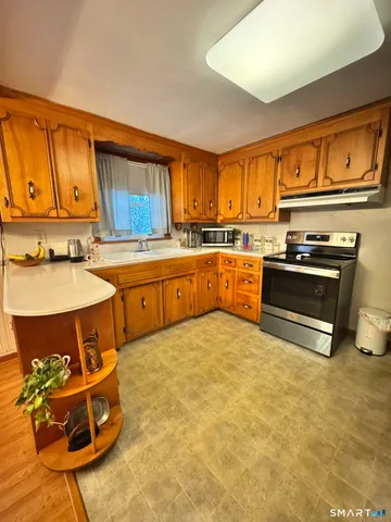 a kitchen with stainless steel appliances granite countertop a stove a sink dishwasher and a refrigerator with wooden cabinets