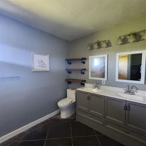 a bathroom with a toilet sink vanity and mirror