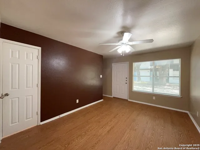 an empty room with windows and fan