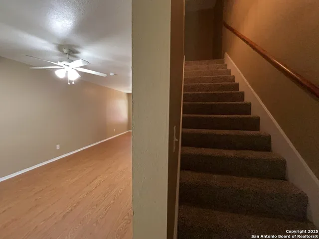 an empty room with windows and chandelier fan