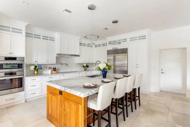 a kitchen with stainless steel appliances granite countertop a table chairs and white cabinets
