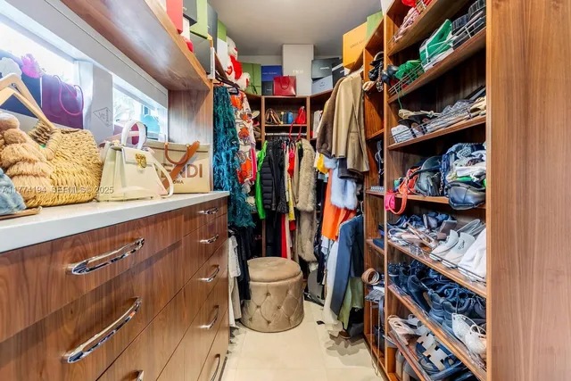 a view of walk in closet with clothes and shoes