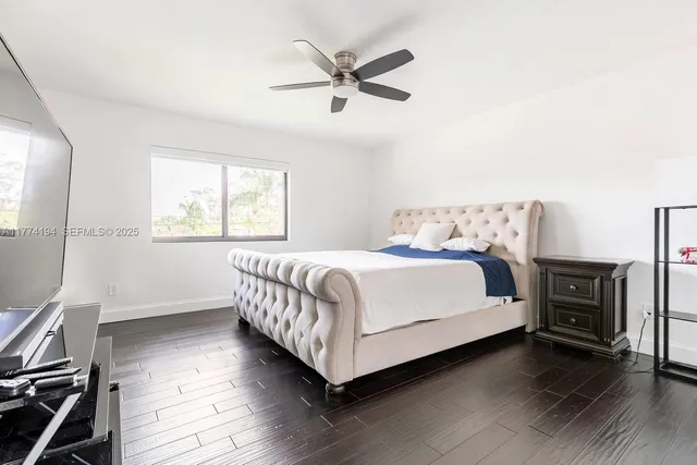 a bedroom with a bed and a ceiling fan with wooden floor
