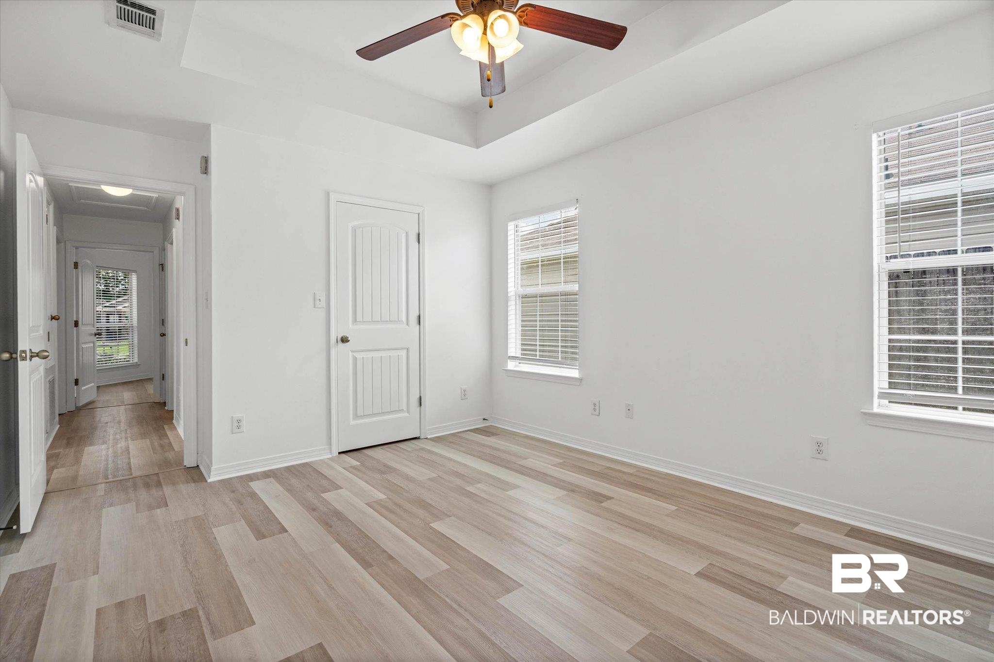 8980 Spring Grove North Mobile, AL 36695 - Photo 9 of 24 Spacious room featuring light-toned wood-finish flooring, white walls, and a tray ceiling with a ceiling fan