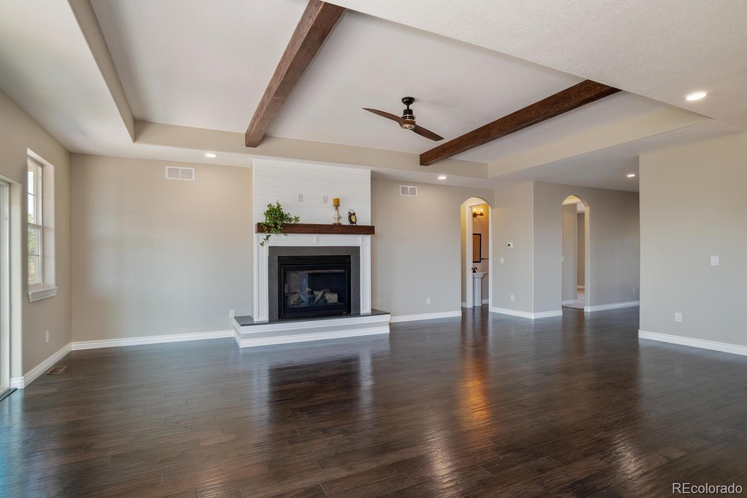 1726 Virginia Drive Fort Lupton, CO 80621 - Photo 4 of 36 an empty room with wooden floor a fireplace and windows