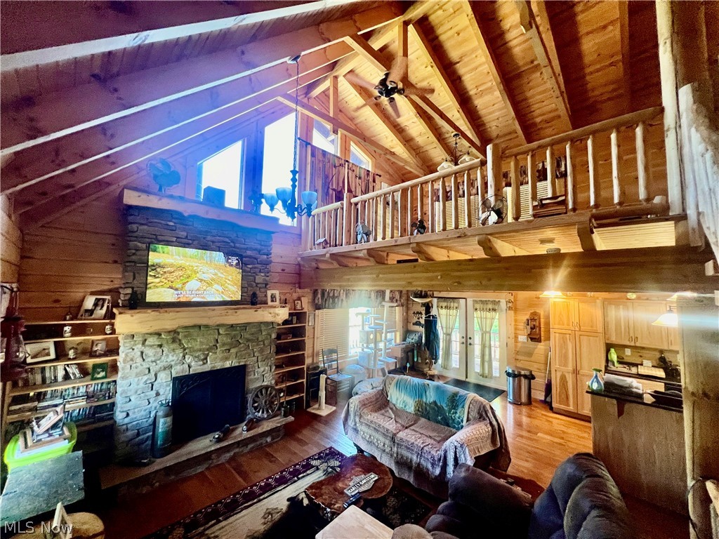 39589 National Road Bethesda, OH 43719 - Photo 16 of 35 Living room featuring wooden walls, a stone fireplace, a wealth of natural light, and wooden ceiling