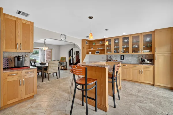a kitchen with stainless steel appliances granite countertop a stove top oven a sink a dining table and chairs