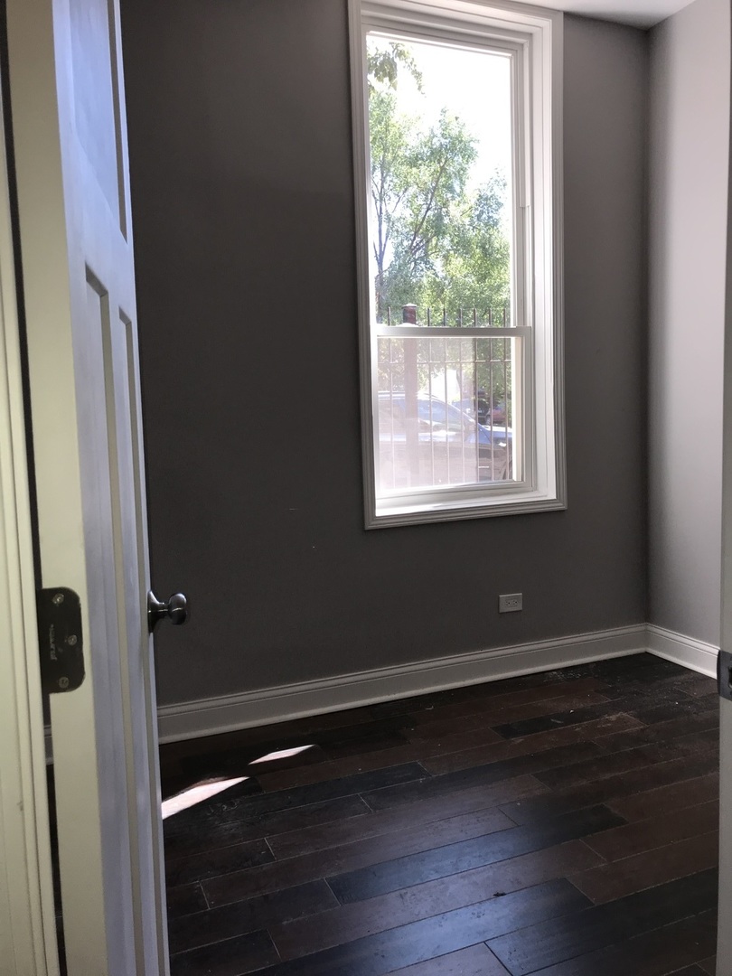 2734 West 18th Street, Unit 1F Chicago, IL 60608 - Photo 14 of 14 a view of an empty room with wooden floor and a window