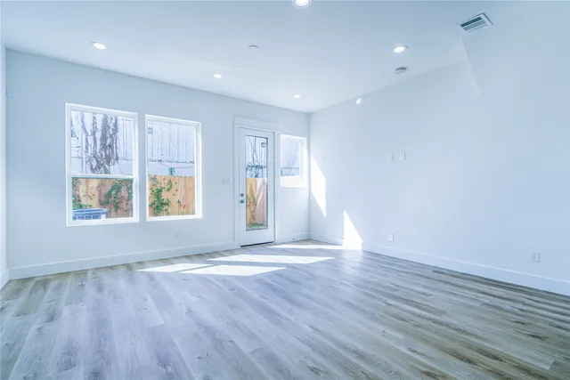 an empty room with wooden floor and windows