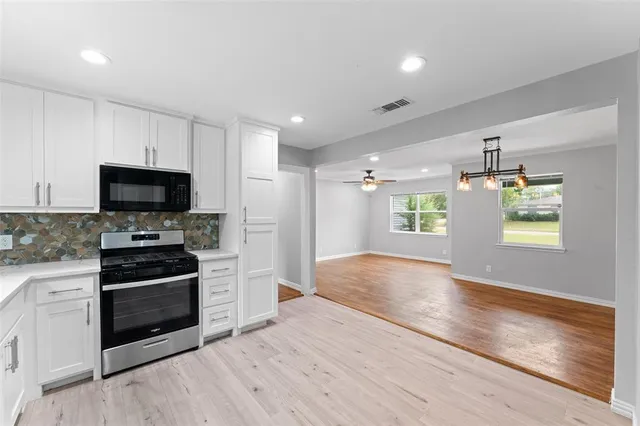a view of a kitchen with a sink stove cabinets and empty room