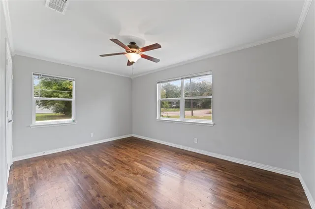 a view of an empty room with a window and wooden floor