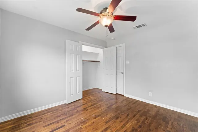 an empty room with wooden floor chandelier fan and closet area