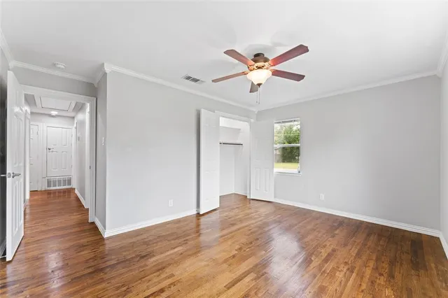 a view of an empty room with window and wooden floor