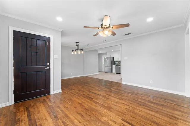 a view of empty room with wooden floor and ceiling fan