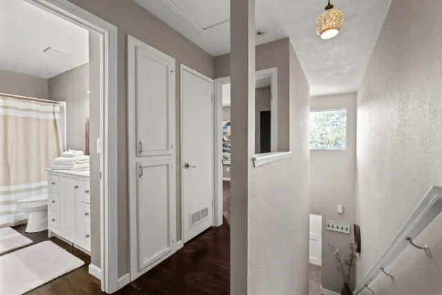 a view of a hallway with bathroom and wooden floor