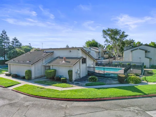 a front view of a house with a garden and trees