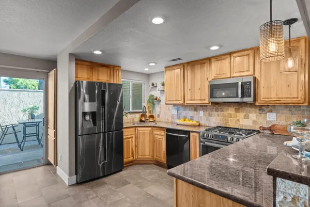 a kitchen with stainless steel appliances granite countertop a refrigerator a stove top oven a sink and dishwasher