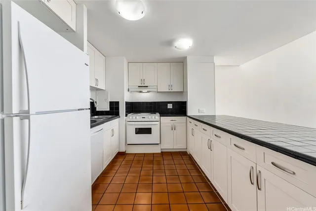 a kitchen with granite countertop white cabinets and white appliances