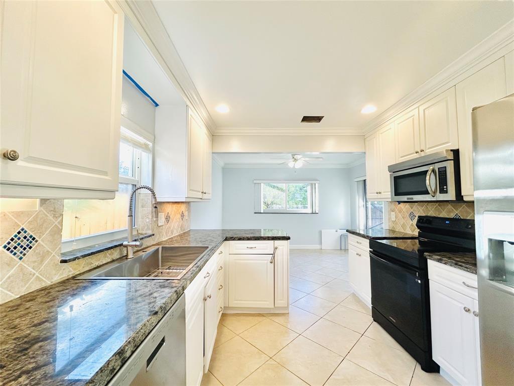 8948 Southwest 18th Road Boca Raton, FL 33433 - Photo 12 of 24 a kitchen with granite countertop a sink a stove top oven and cabinetry