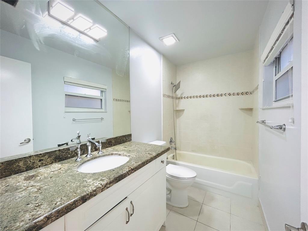 8948 Southwest 18th Road Boca Raton, FL 33433 - Photo 20 of 24 a bathroom with a granite countertop sink a toilet a mirror and shower