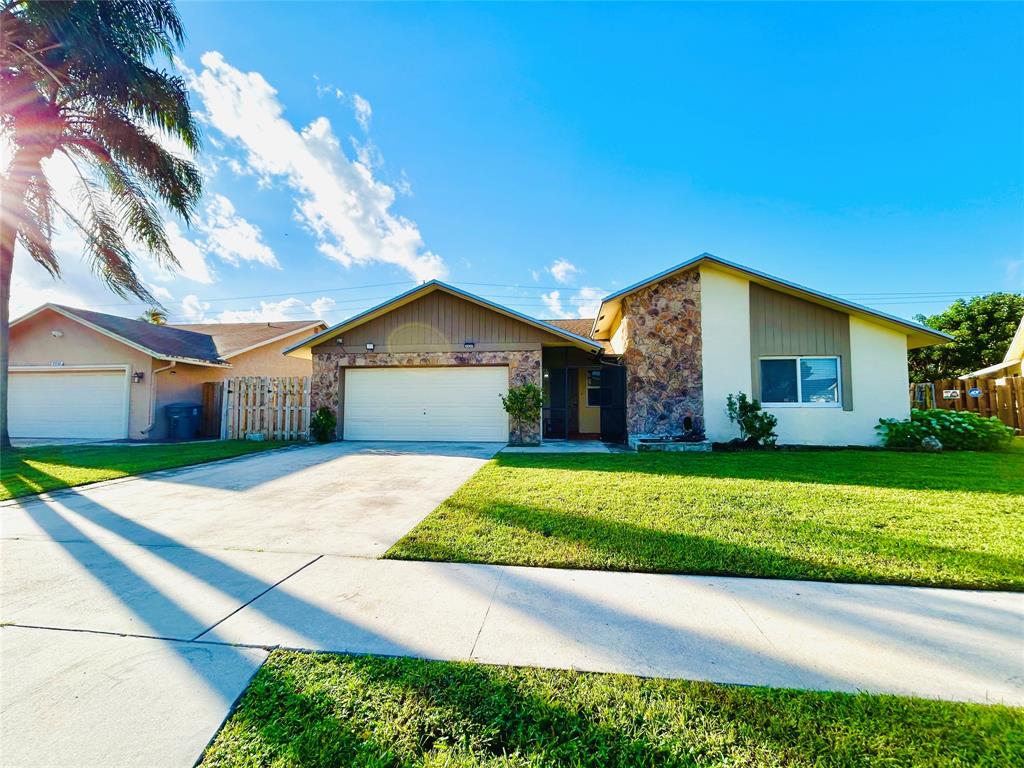 8948 Southwest 18th Road Boca Raton, FL 33433 - Photo 2 of 24 a front view of a house with a yard and garage