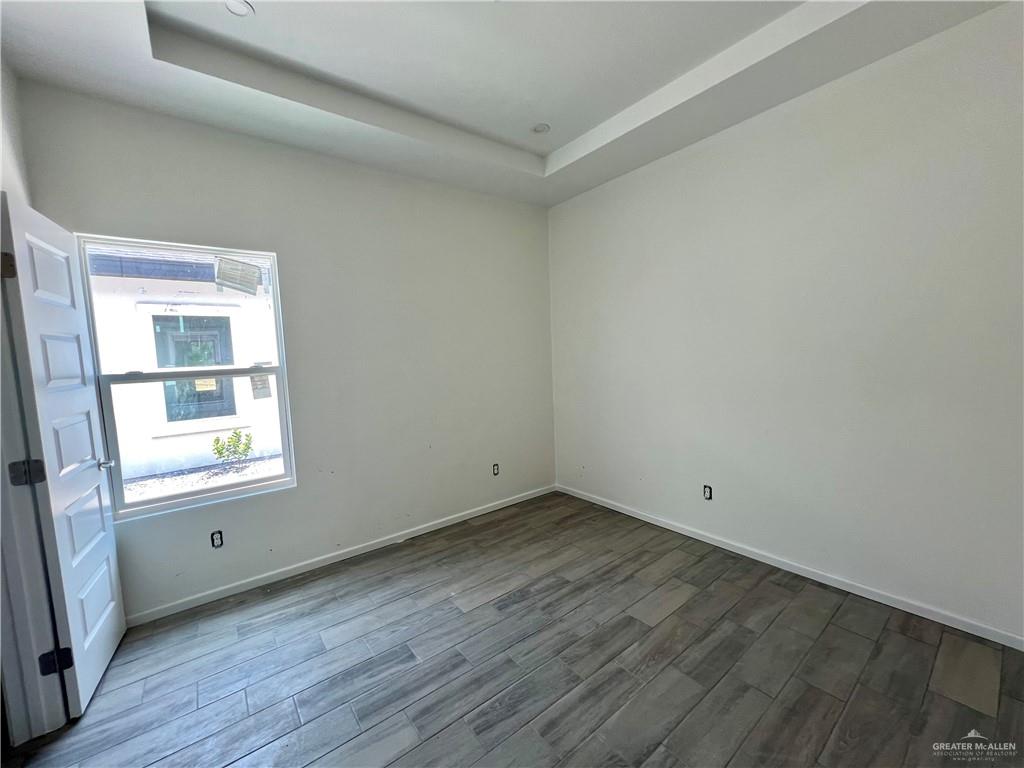 1821 Monaco Drive, Unit 2 San Juan, TX 78589 - Photo 11 of 16 an empty room with wooden floor and windows