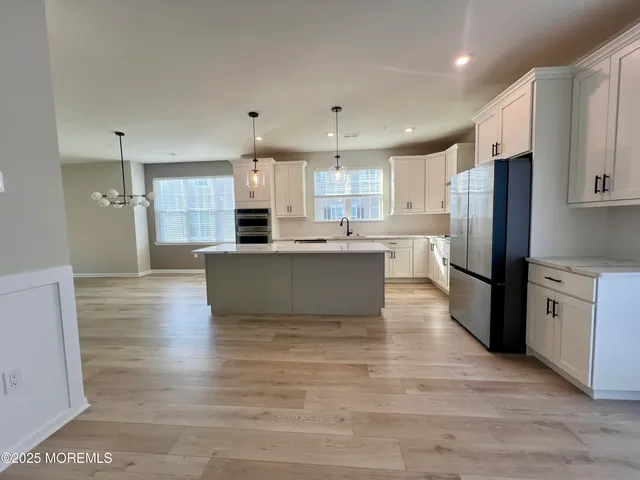 a kitchen with stainless steel appliances granite countertop a refrigerator sink and white cabinets
