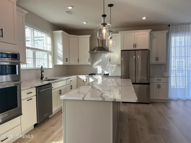 a kitchen with kitchen island a counter top space a sink stainless steel appliances and cabinets