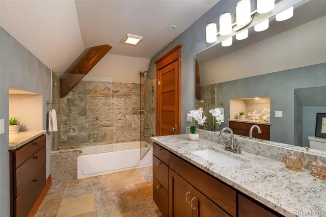 a bathroom with a granite countertop sink a large mirror and a bathtub