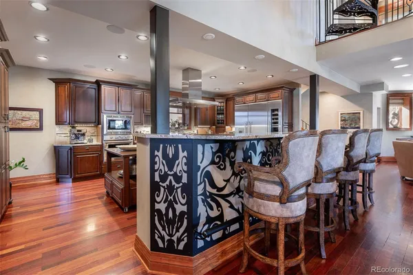a living room with stainless steel appliances kitchen island granite countertop furniture wooden floor and a kitchen view