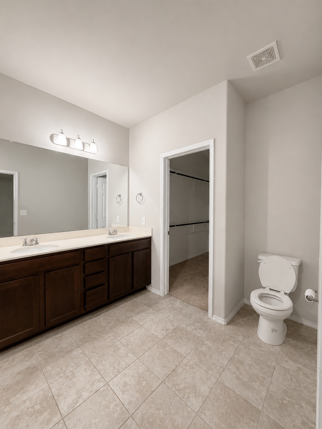 187 Limerick Road Buda, TX 78610 - Photo 10 of 18 A spacious primary bathroom boasts a dual-sink vanity and tiled flooring, with a walk-in closet beyond.