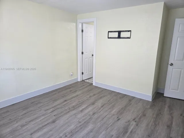 an empty room with wooden floor and closet area