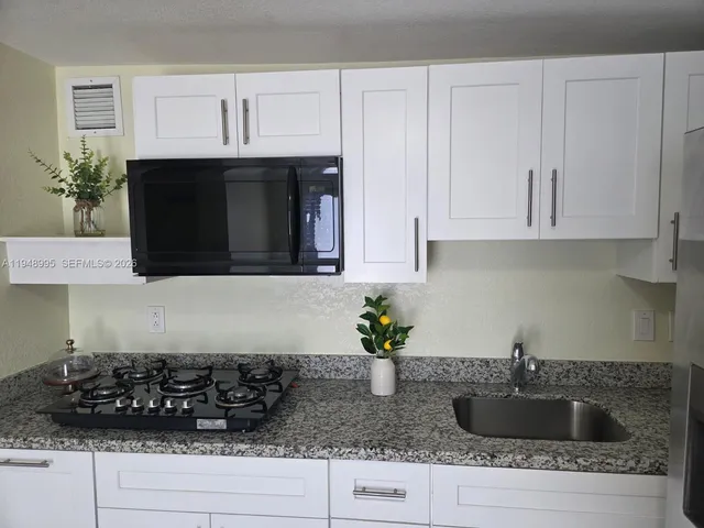 a kitchen with stainless steel appliances granite countertop a sink a stove and cabinets