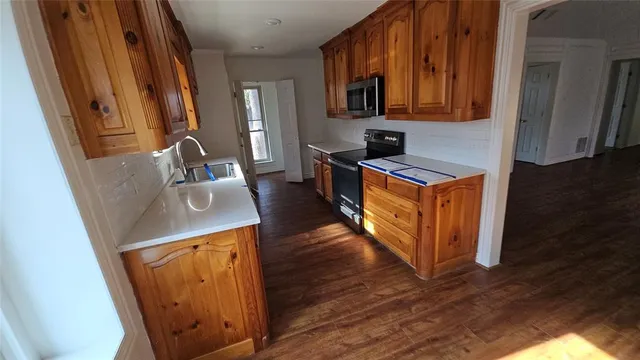 a kitchen with sink a refrigerator and wooden cabinets