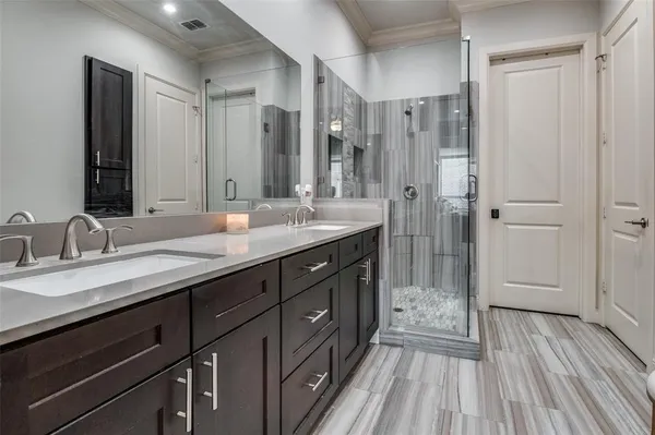 a spacious bathroom with a granite countertop double vanity sink a mirror and a shower