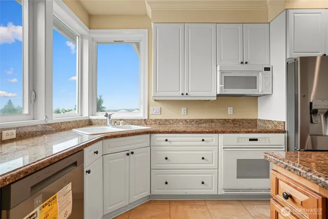 a kitchen with granite countertop white cabinets and stainless steel appliances