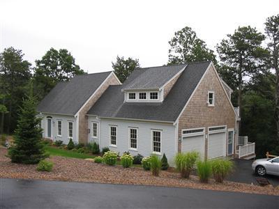 700 Satucket Road Brewster, MA 02631 - Photo 8 of 9 a front view of a house with a yard and garage