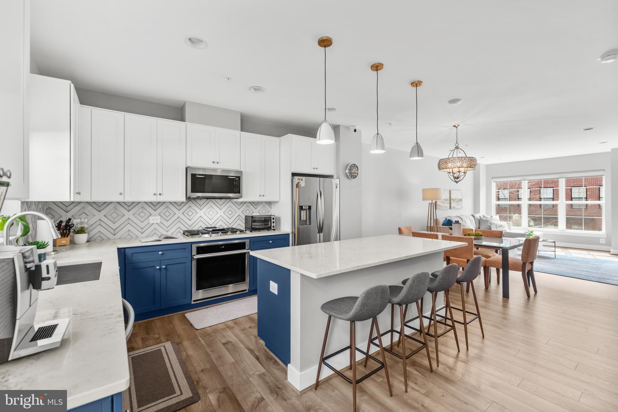 11226 Beaker Street Reston, VA 20190 - Photo 11 of 53 a kitchen with stainless steel appliances granite countertop a stove a refrigerator a kitchen island a dining table and chairs with wooden floor