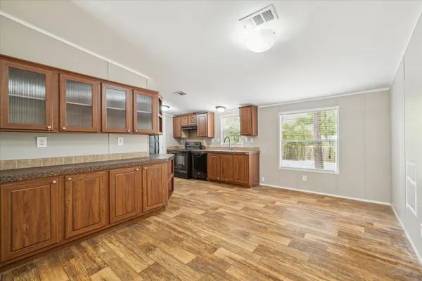 a large kitchen with stainless steel appliances granite countertop a stove a sink dishwasher and a microwave oven with white cabinets