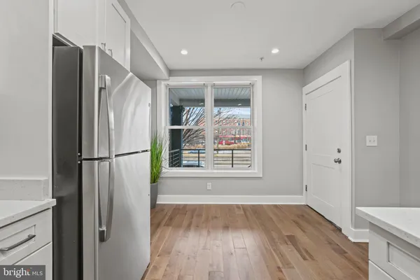 a view of a hallway with wooden floor and a refrigerator