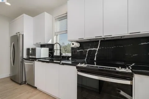 a view of kitchen with stainless steel appliances wooden floor and windows