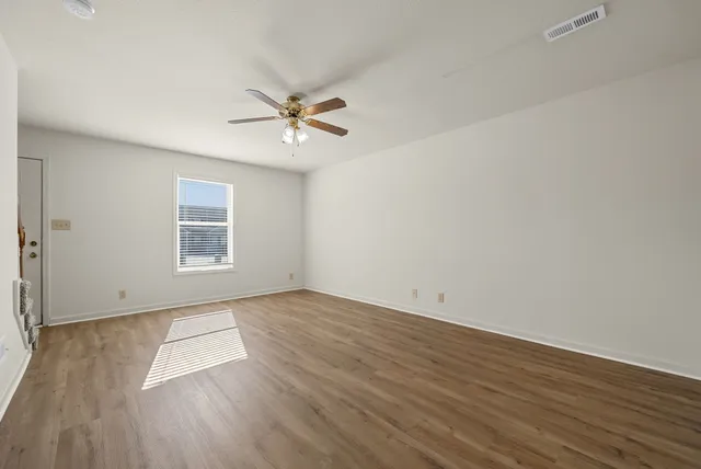 an empty room with wooden floor and windows