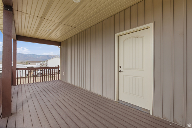 2567 West Rim Rock Drive Stockton, UT 84071 - Photo 43 of 64 Covered porch featuring a wood-finish deck, brown railing, and beige vertical siding
