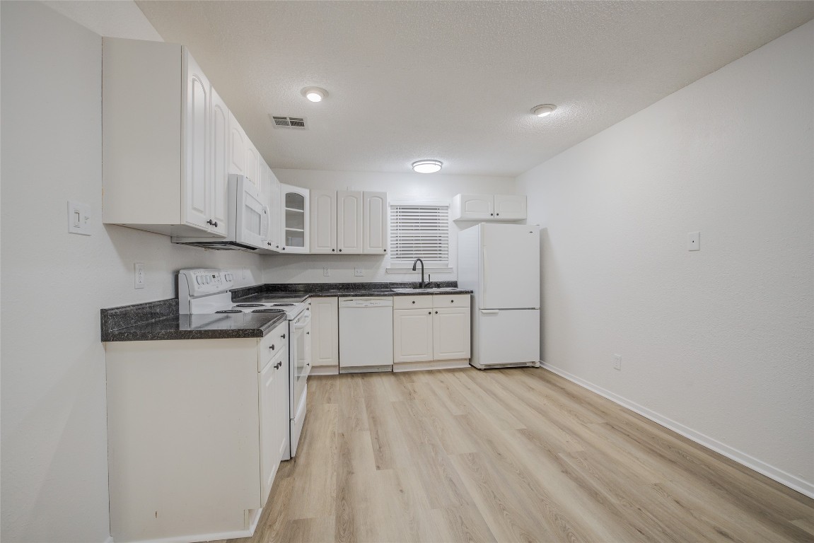 8600 Fathom Circle, Unit 1303 Austin, TX 78750 - Photo 14 of 30 a kitchen with granite countertop white cabinets and white appliances