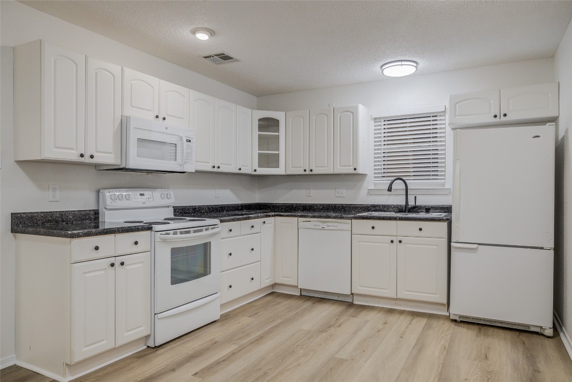 8600 Fathom Circle, Unit 1303 Austin, TX 78750 - Photo 15 of 30 a kitchen with granite countertop white cabinets white appliances and sink
