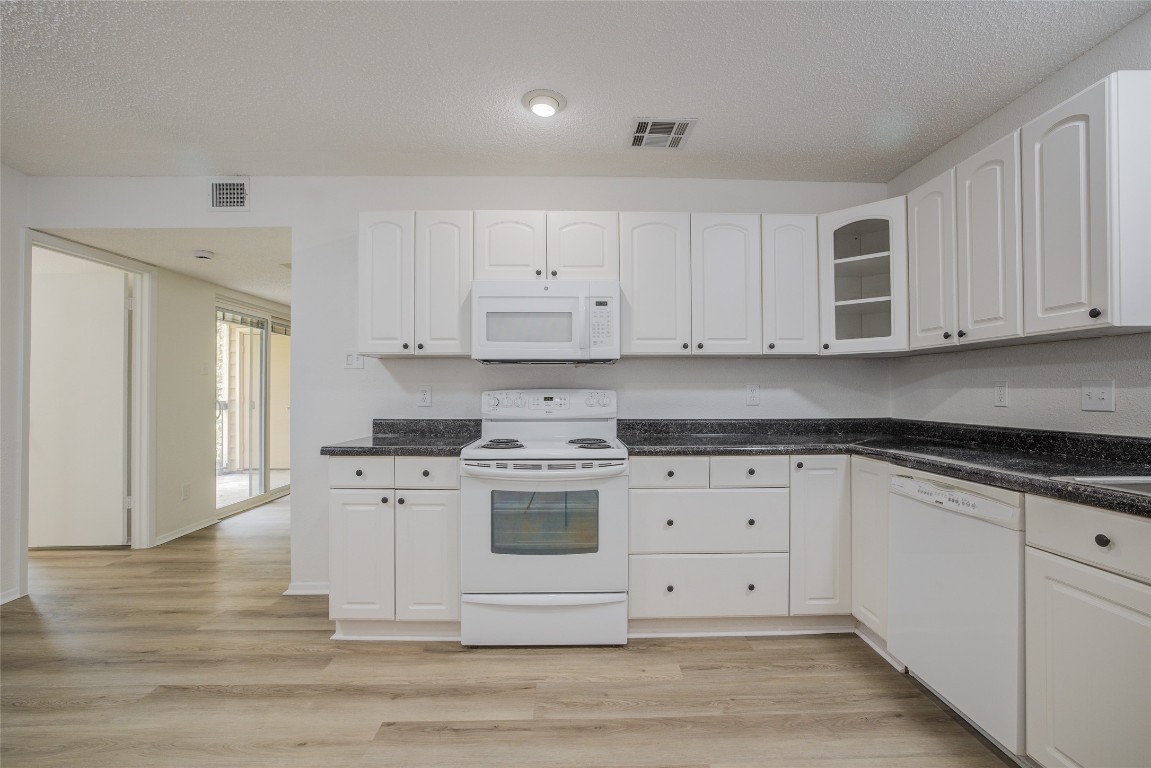 8600 Fathom Circle, Unit 1303 Austin, TX 78750 - Photo 16 of 30 a kitchen with stainless steel appliances granite countertop a stove a sink and white cabinets