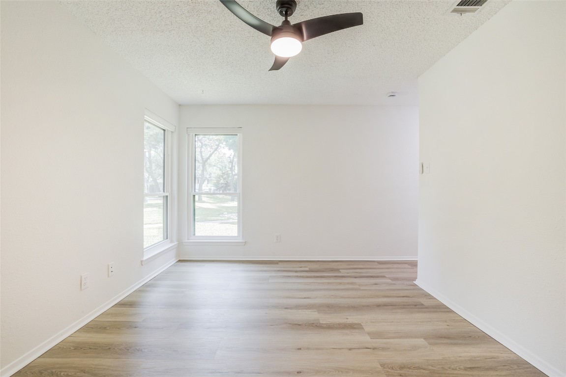 8600 Fathom Circle, Unit 1303 Austin, TX 78750 - Photo 22 of 30 an empty room with wooden floor fan and windows
