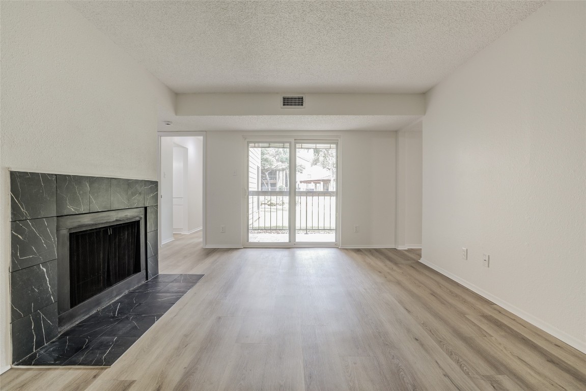 8600 Fathom Circle, Unit 1303 Austin, TX 78750 - Photo 5 of 30 an empty room with wooden floor fireplace and windows