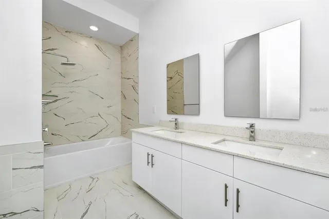 a bathroom with a sink double vanity granite tub shower and a mirror