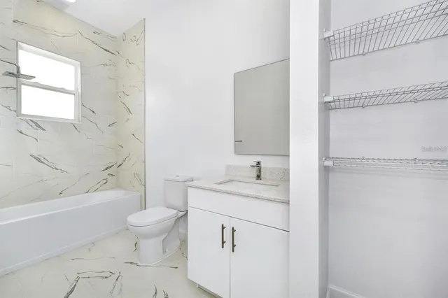 a bathroom with a granite countertop sink toilet a mirror and shower